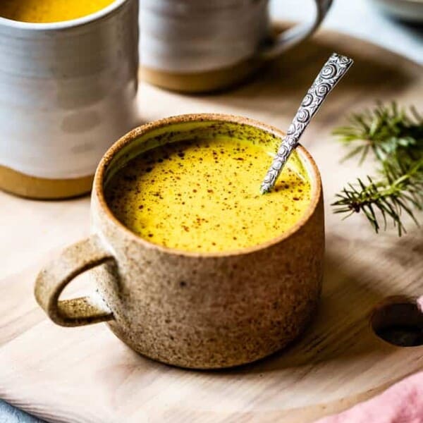 Golden milk in a mug with a spoon in it.