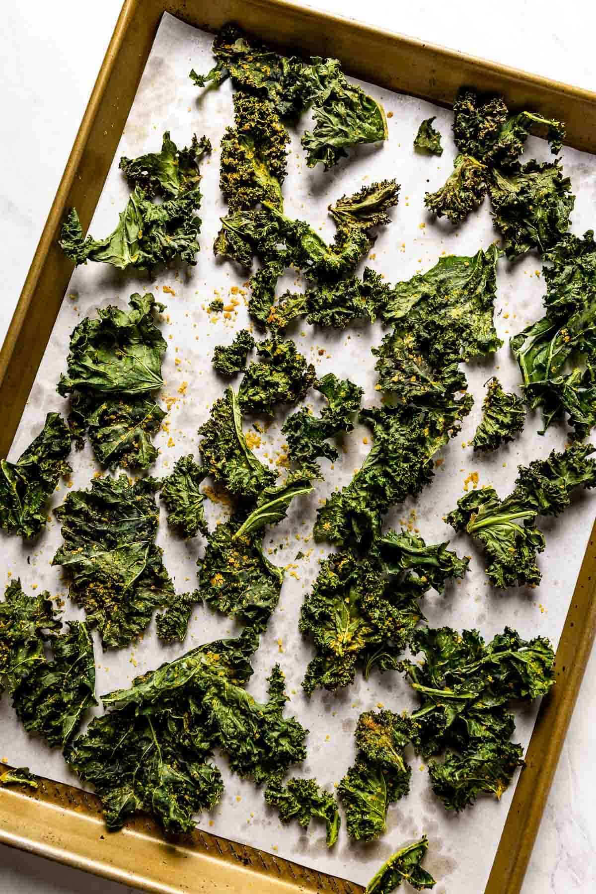 Kale Chips with nutritional yeast after they are baked on a sheet pan.