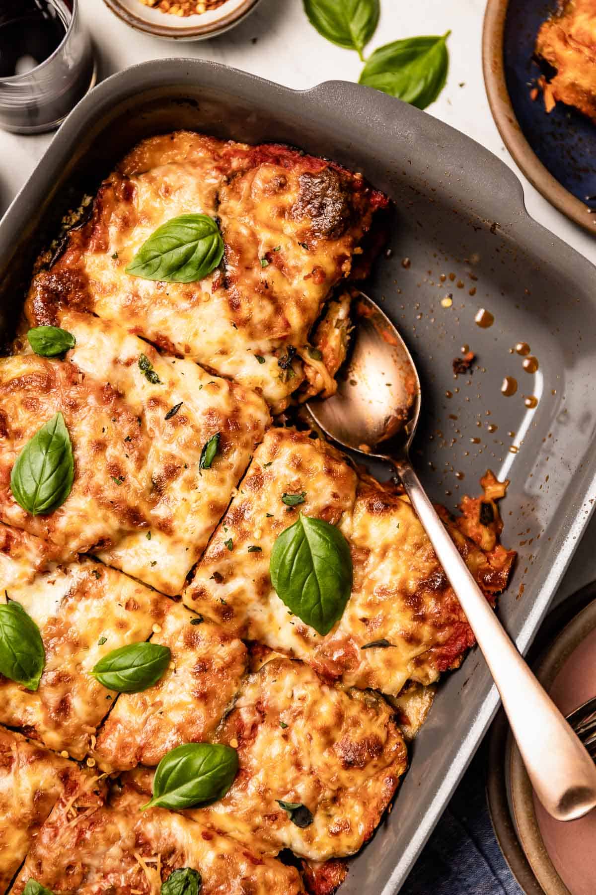 Baked eggplant parm topped with basil in a casserole dish from the top view.
