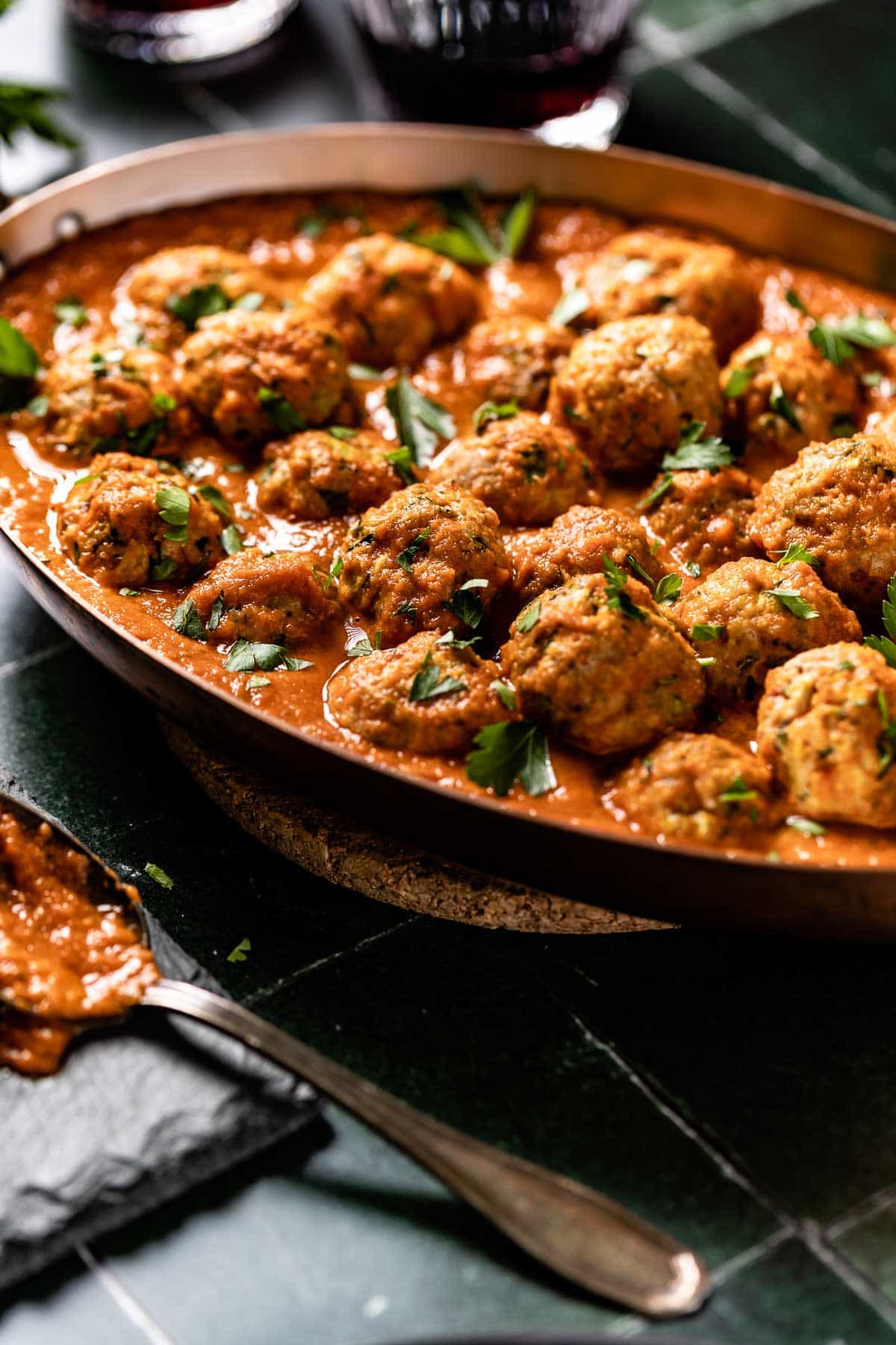 Meatballs made from ground turkey in a pan of sauce shown from the side view.