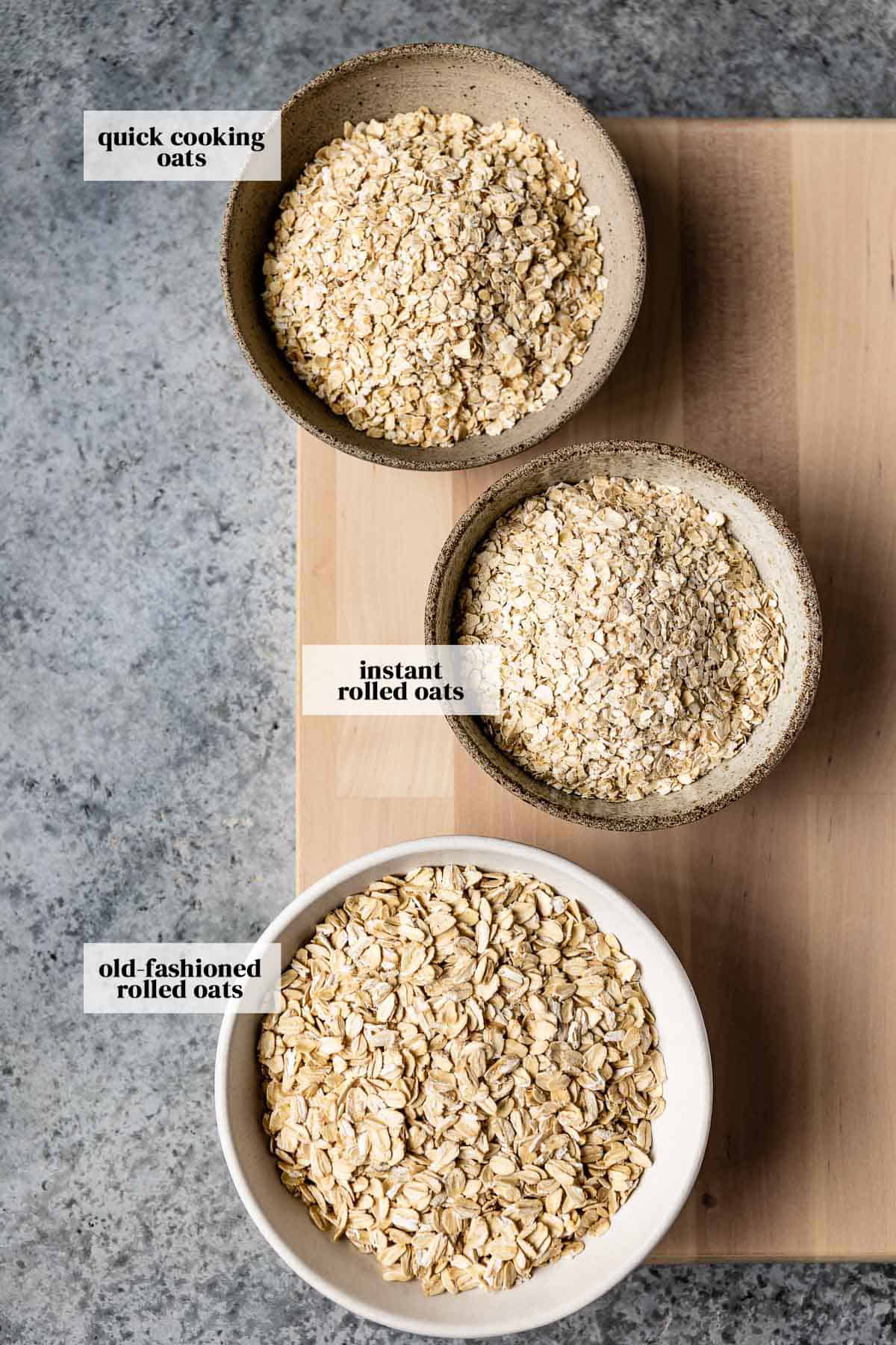 Rolled oats, quick oats, and instant oats in small bowls from the top view.