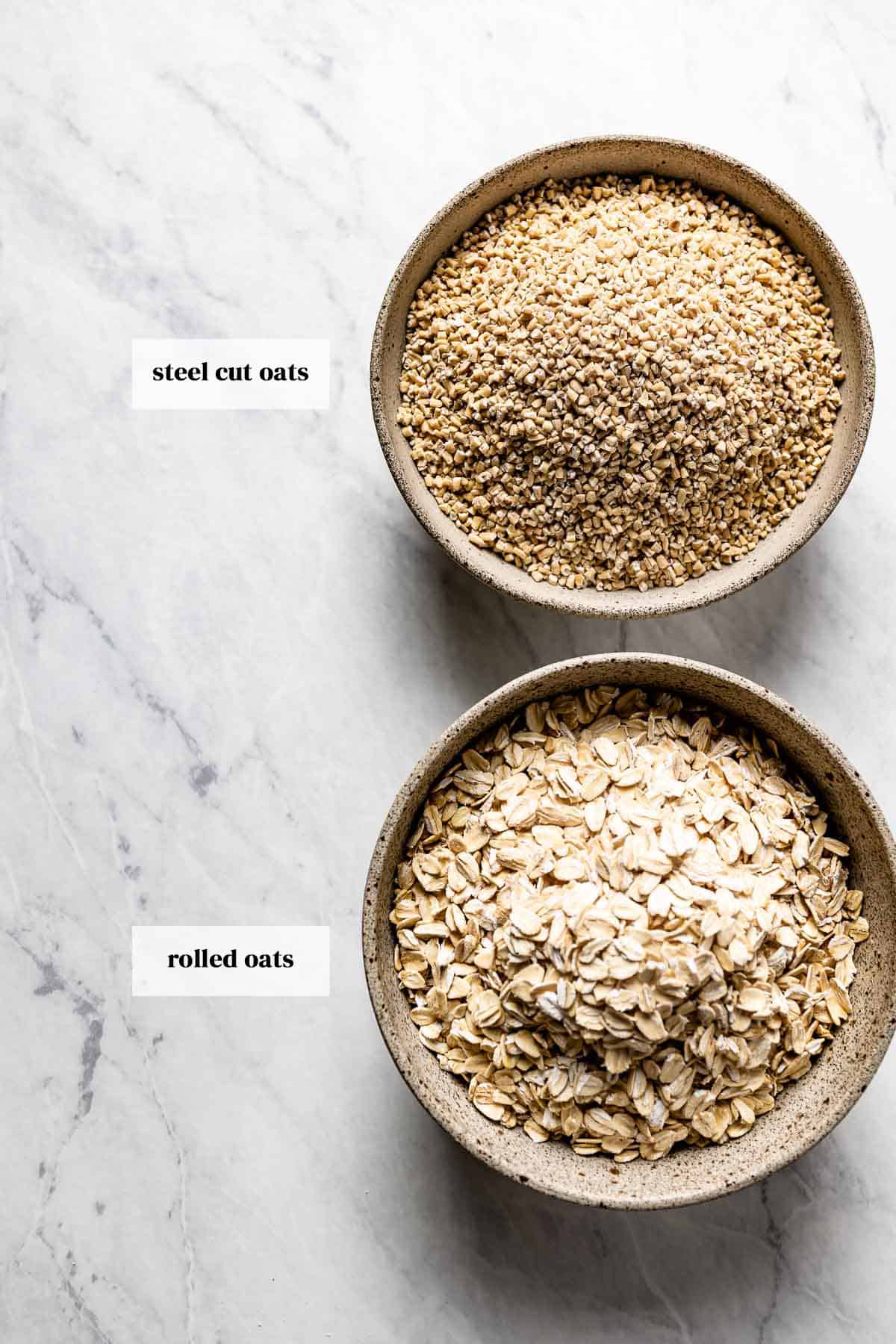 A bowl of steel cut oat and another one with regular oats from the top view.