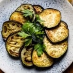 Sauteed eggplant on a plate garnished with parsley.