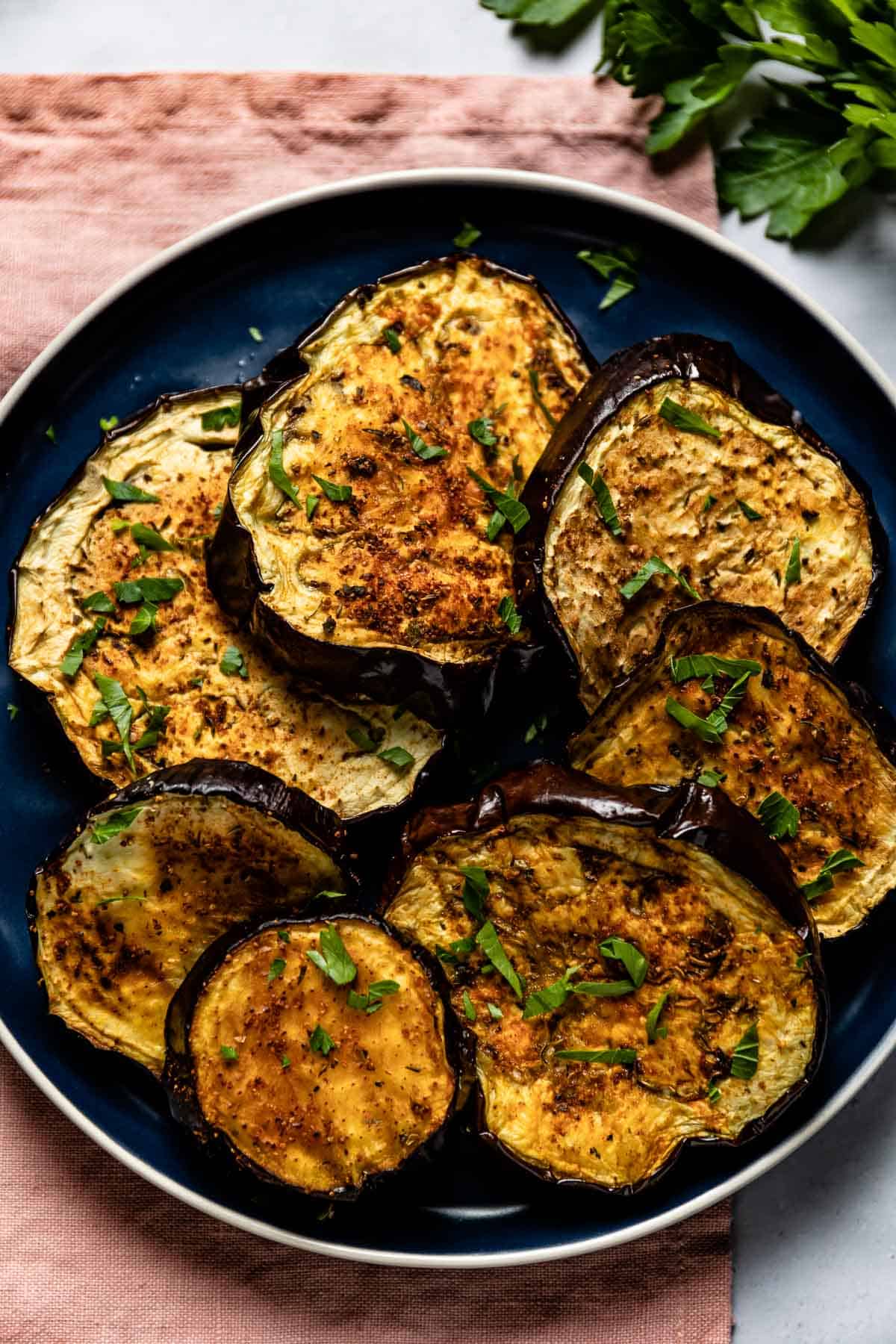 Air fried eggplant slices on a plate from the top view.