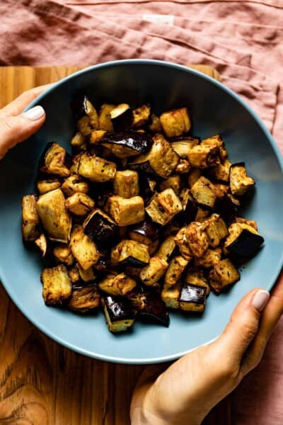 Air fryer eggplant in a bowl being served by a person.
