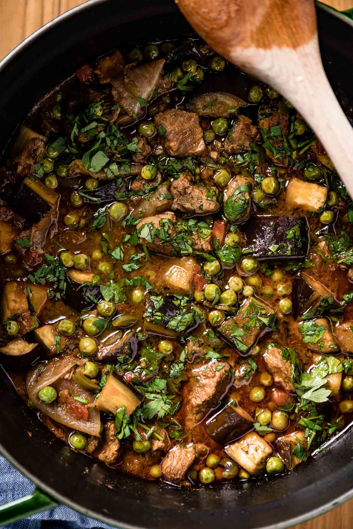 Turkish Style eggplant beef stew after it is cooked in a big pot with a wooden spoon on the side.