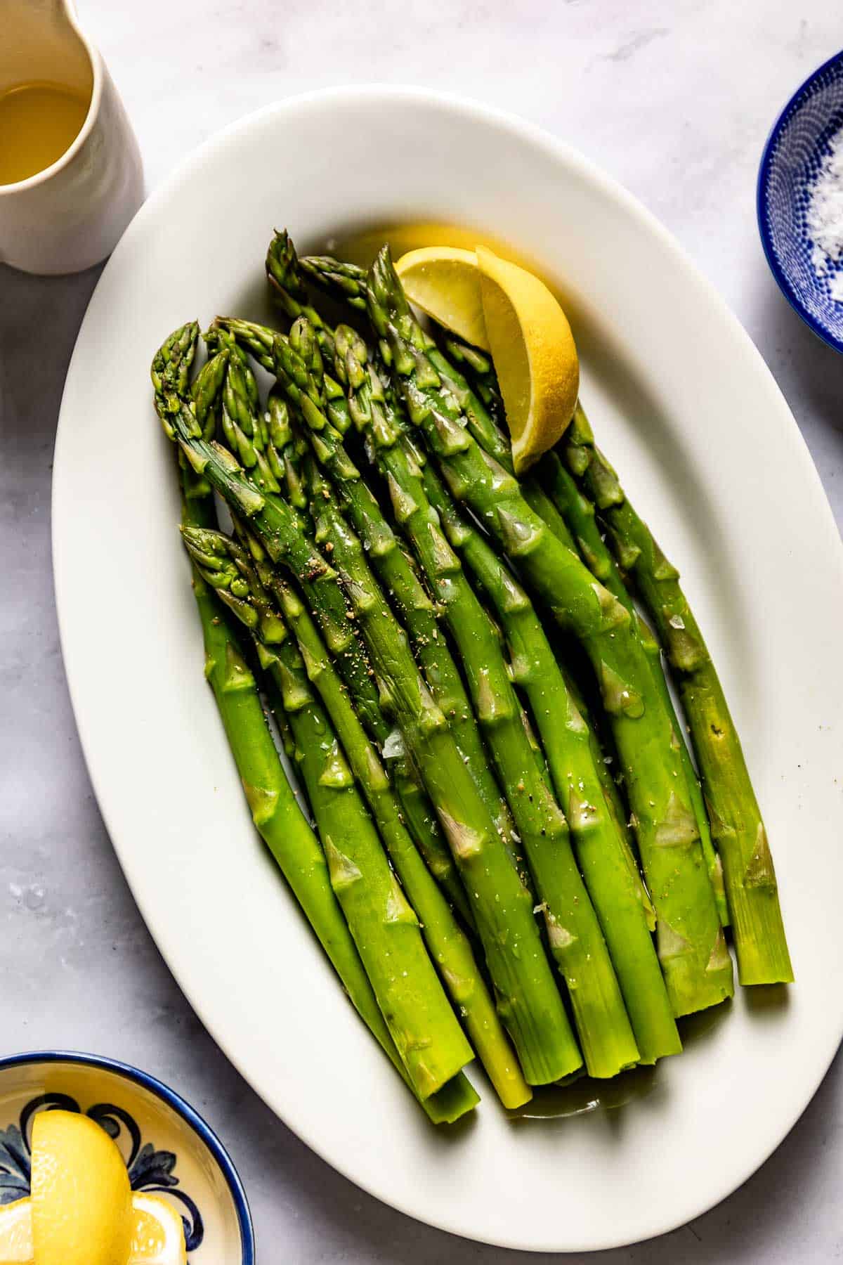 Steamed asparagus on a plated garnished with lemon wedges.