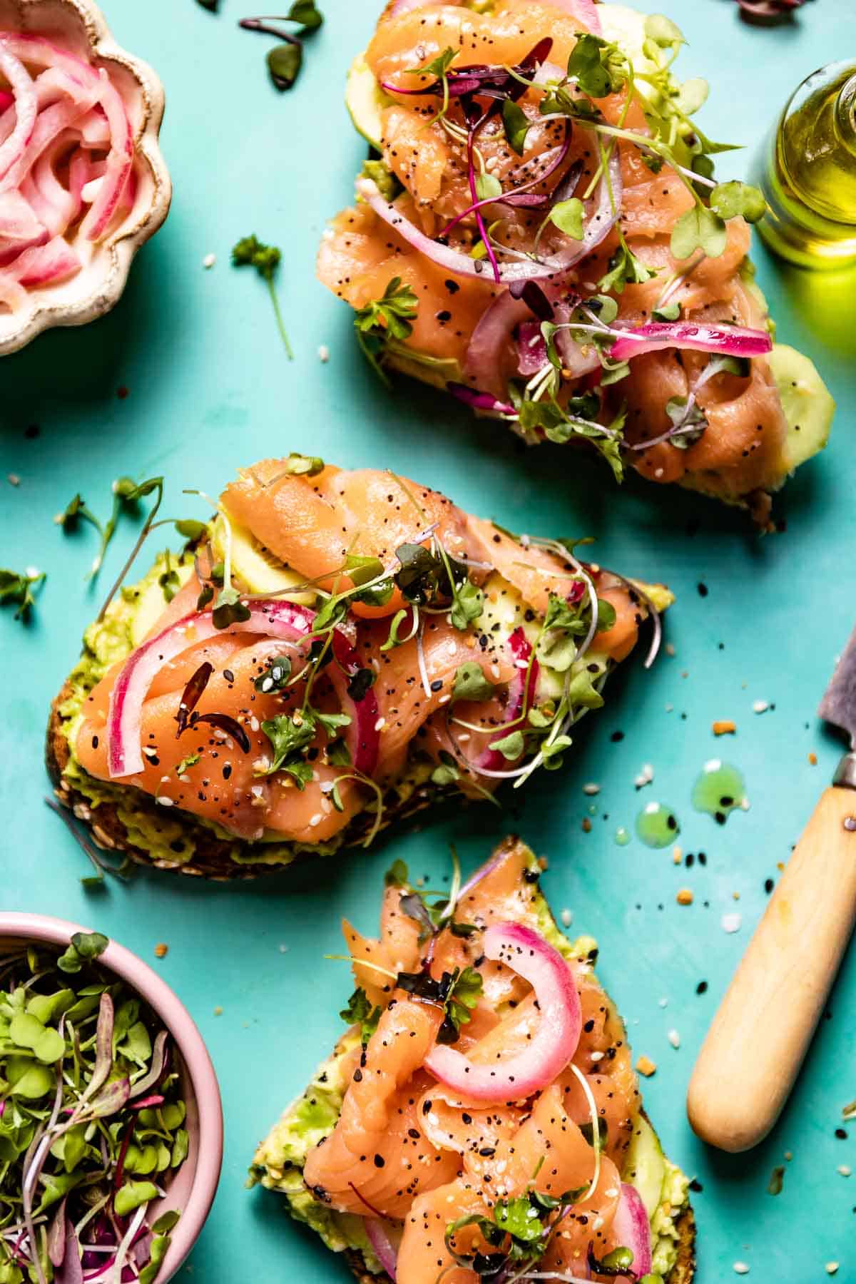 Smoked Salmon and Avocado Toast garnished with red onion and micro greens from the top view.