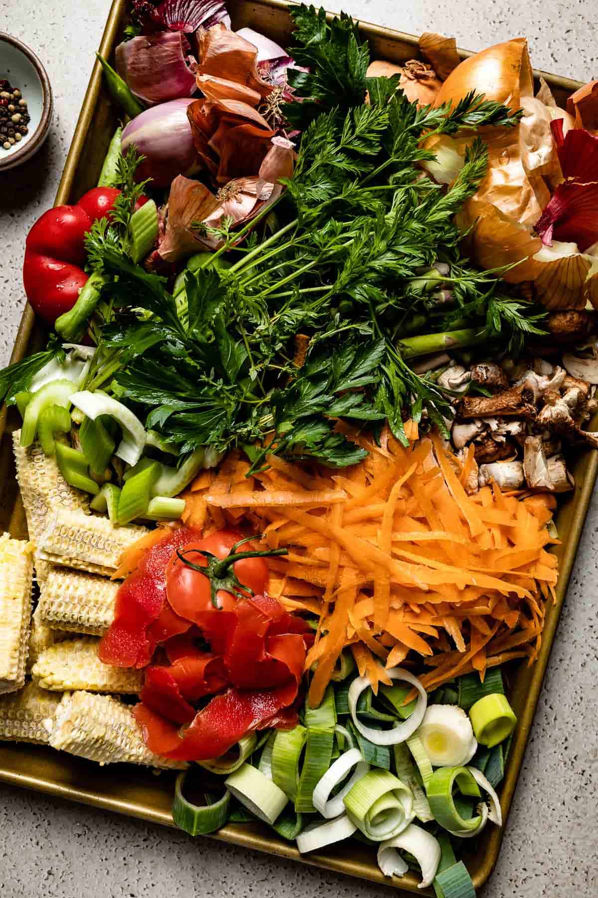 Veggie scraps to use for stock are on a sheet pan from the top view.