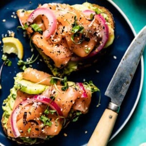 Smoked Salmon Avocado toast on a plate with a knife on the side.