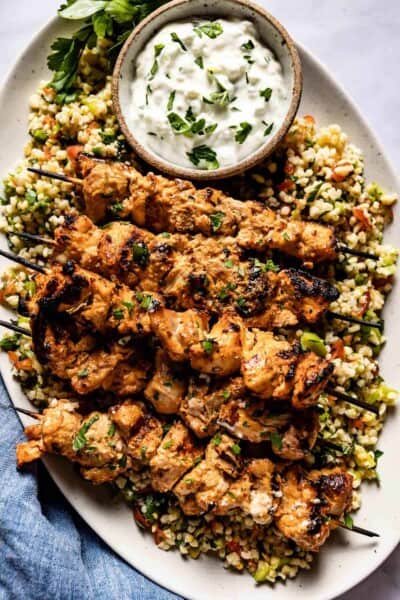 Shish tawook served with yogurt sauce over a bed of tabbouleh from the top view.