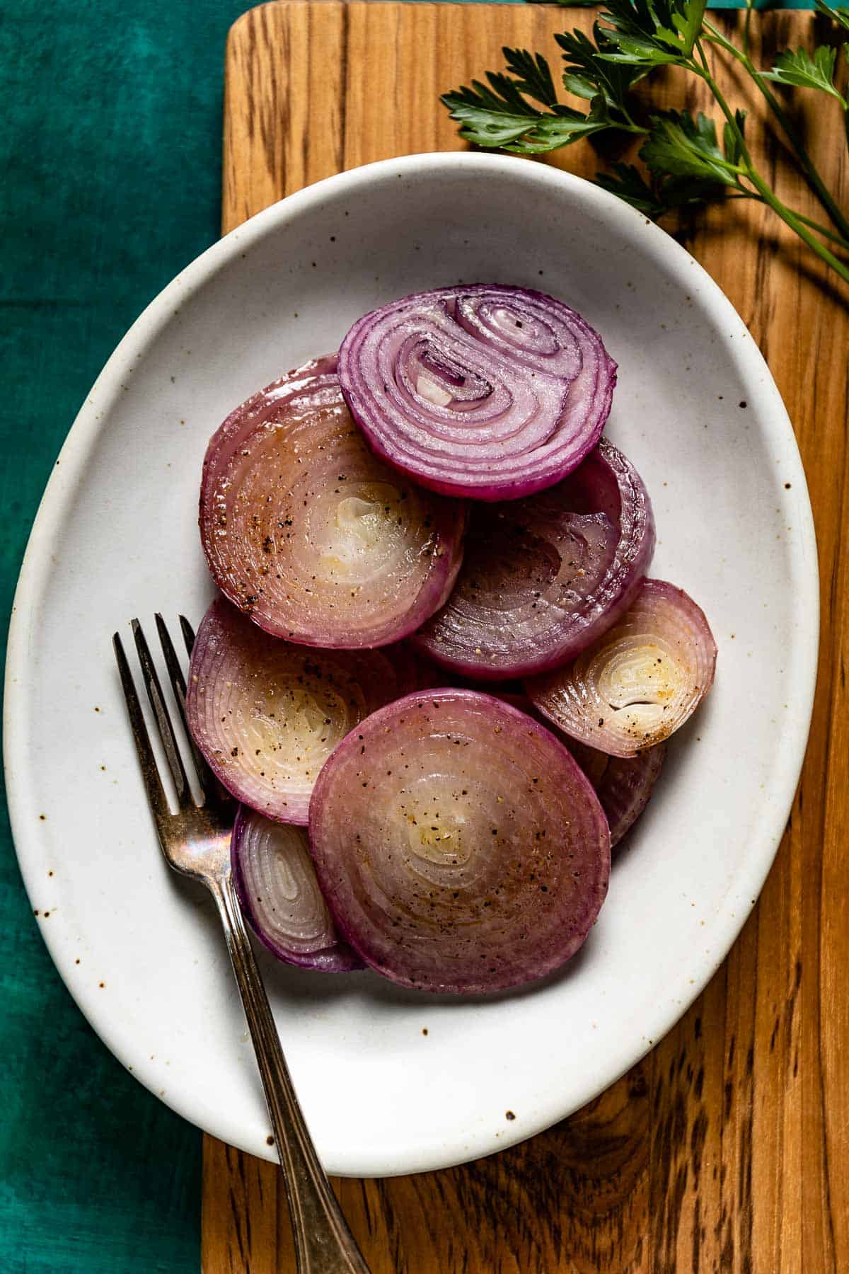 Oven roasted red onions on a plate with a fork on the side.