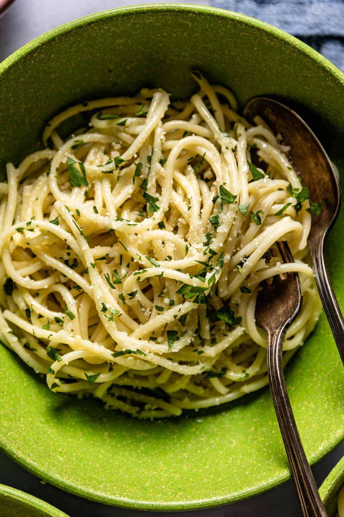 Garlic butter spaghetti in a bowl garnished with parmesan cheese.