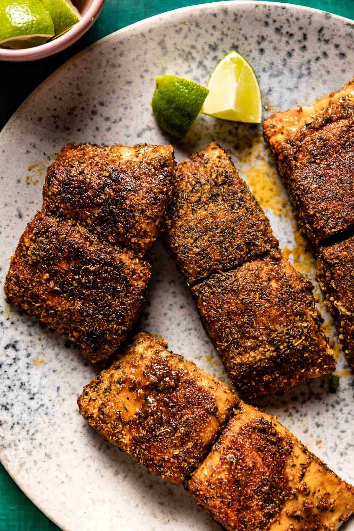 Fish coated with blackened spice mix on a plate from the top view.