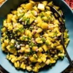 Mango Pineapple Salsa placed in a bowl with a spoon on the side.