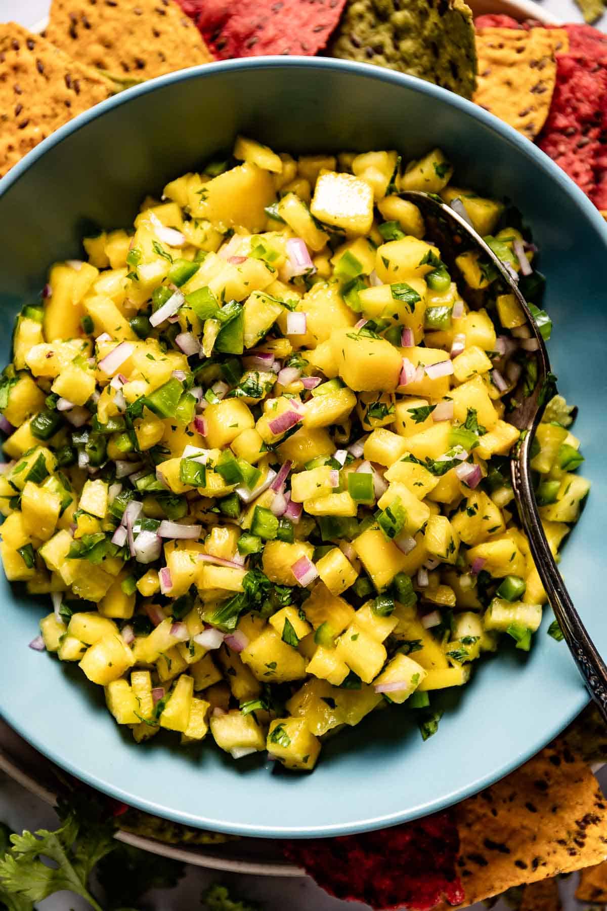 Mango pineapple salsa in a bowl with chips on the side from the top view.