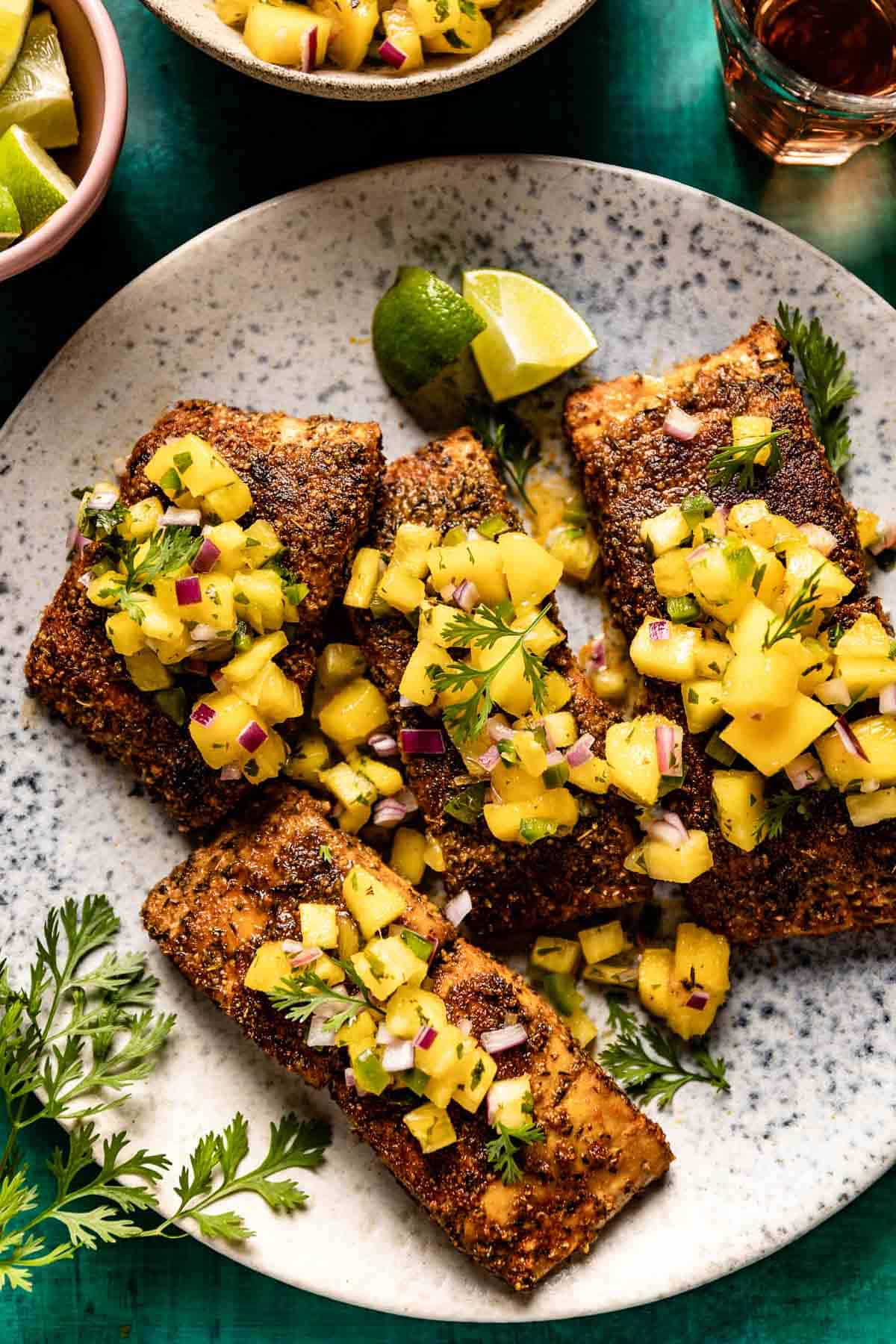 Mango pineapple salsa for fish over blackened mahi mahi on a plate.