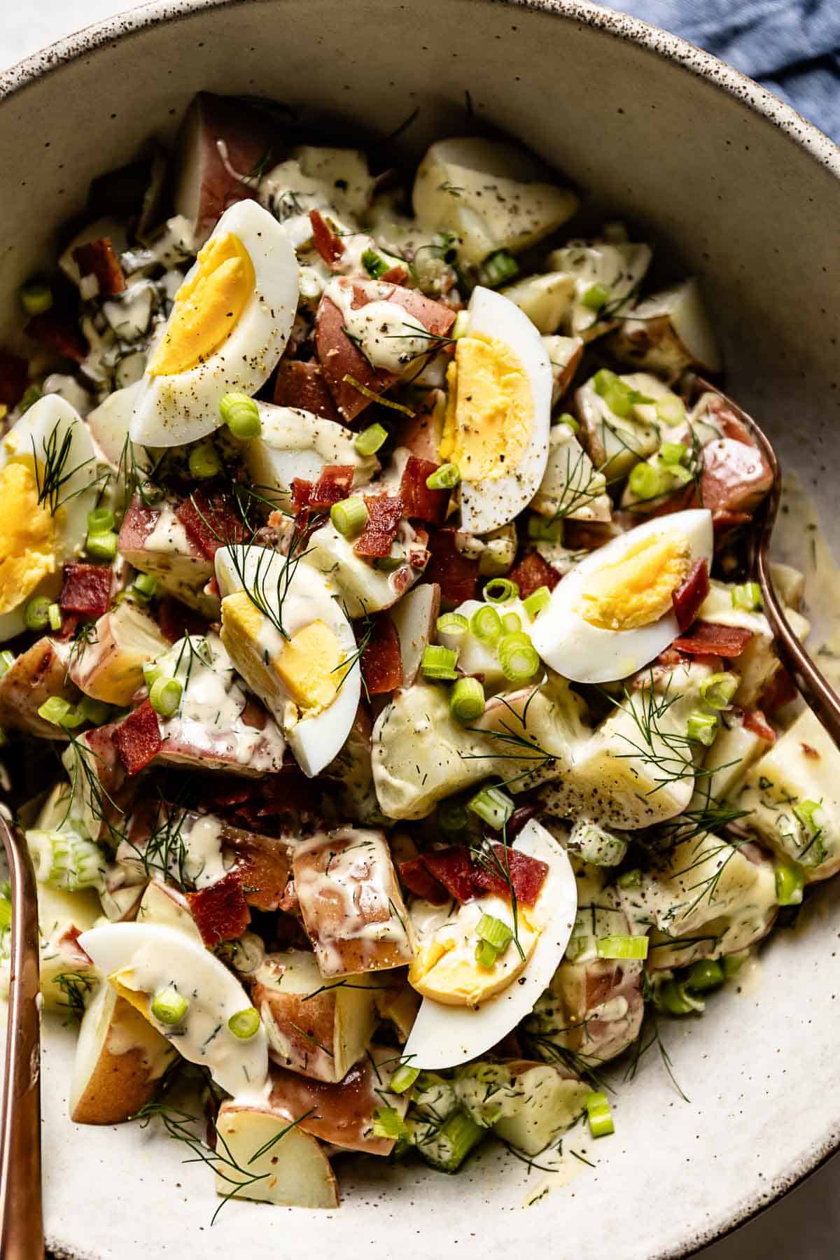 Red potato salad with bacon and eggs in a bowl from the top view.