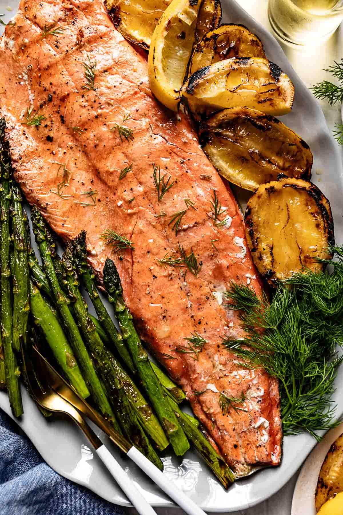 Grilled red salmon with fresh vegetables and herbs on the side.
