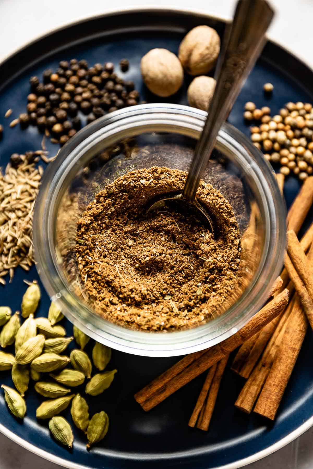 Baharat spice mix in a jar with a spoon in it.