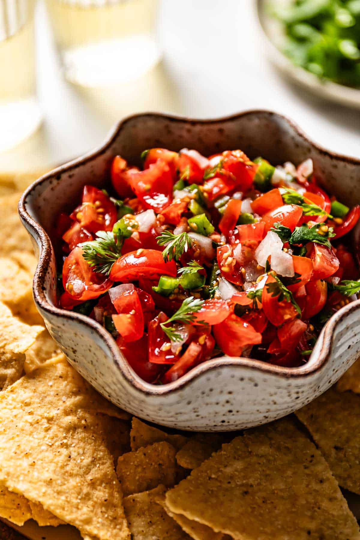 A bowl of cherry tomato salsa with chips on the side.