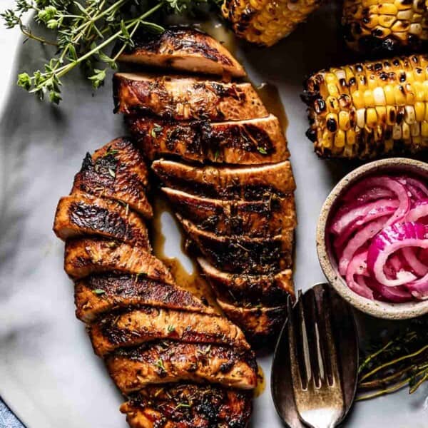 Grilled turkey tenderloins from the top view with grilled corn and pickled red onions on the side.