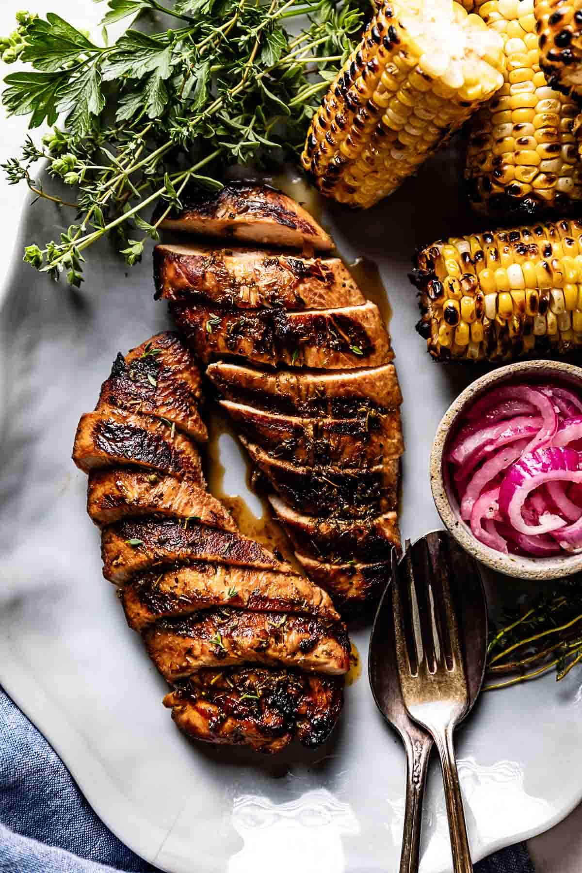 Grilled Turkey Tenderloin served with grilled corn and red onions on a platter.