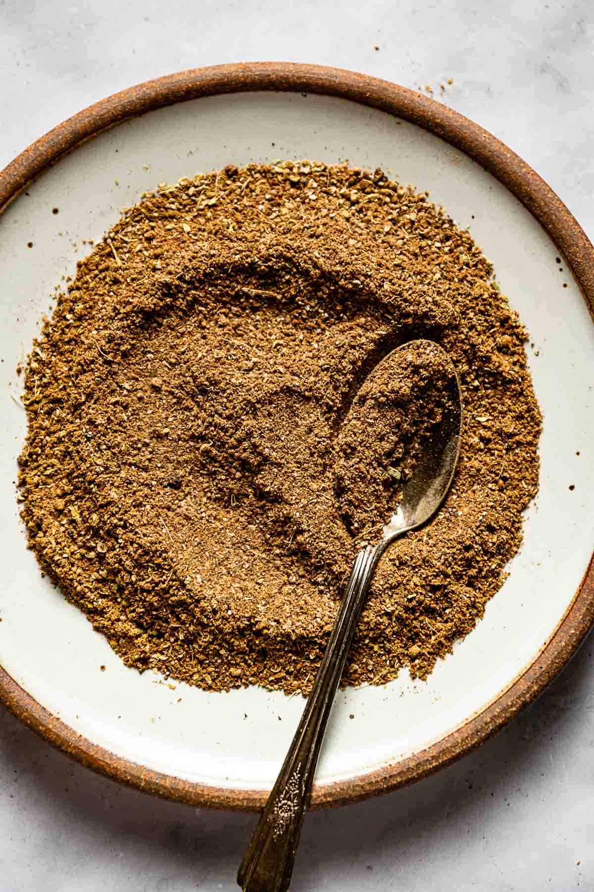 Baharat spice blend mixed in a plate with a spoon on the side.