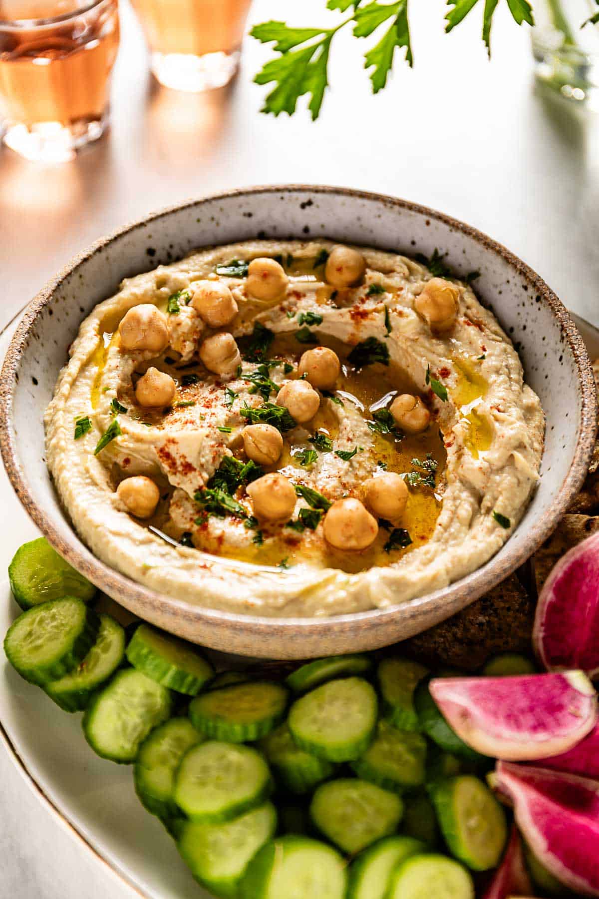 Greek hummus in a bowl garnished with chickpeas and parsley.