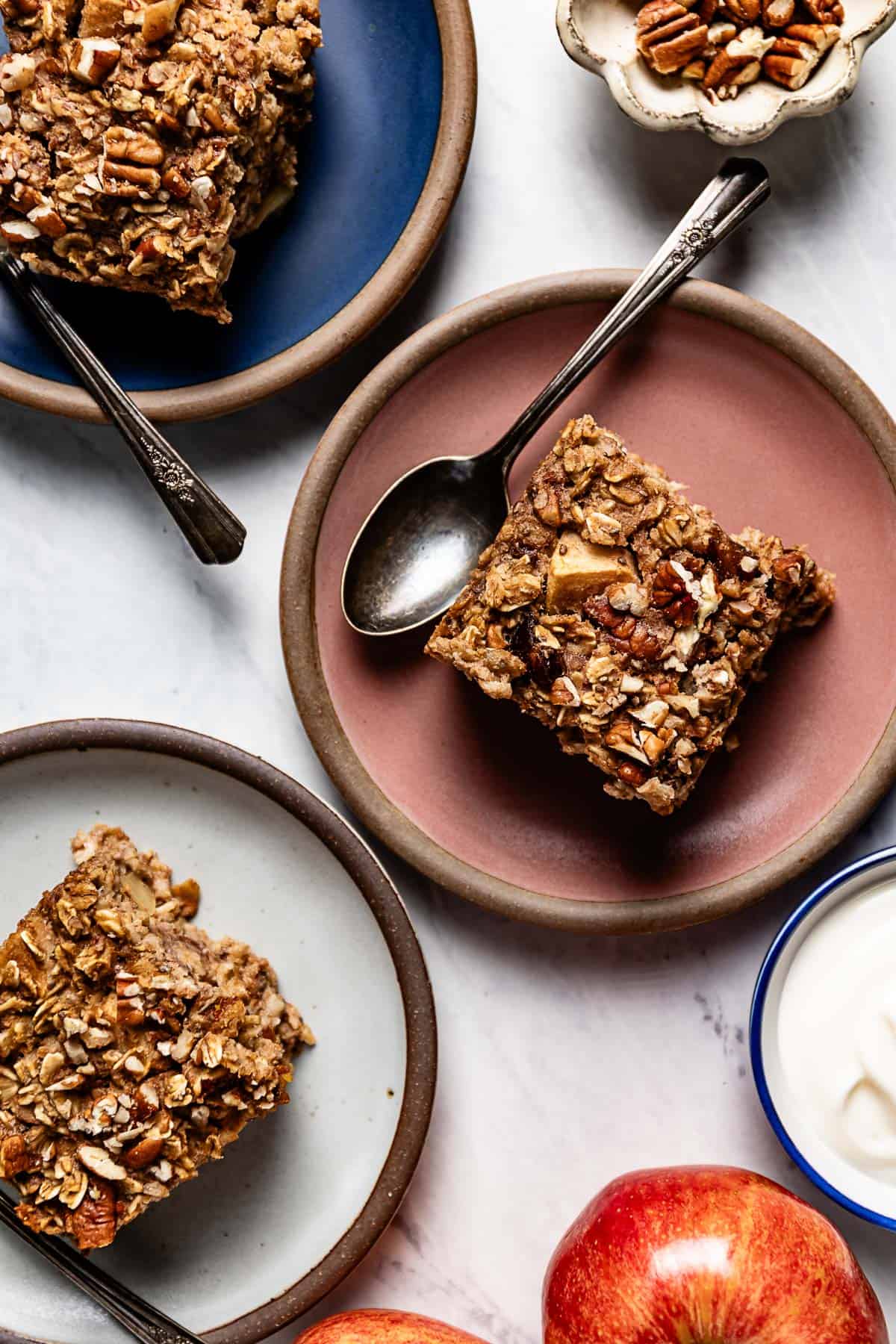 Sliced baked oatmeal with applesauce on a plate with a spoon on the side.