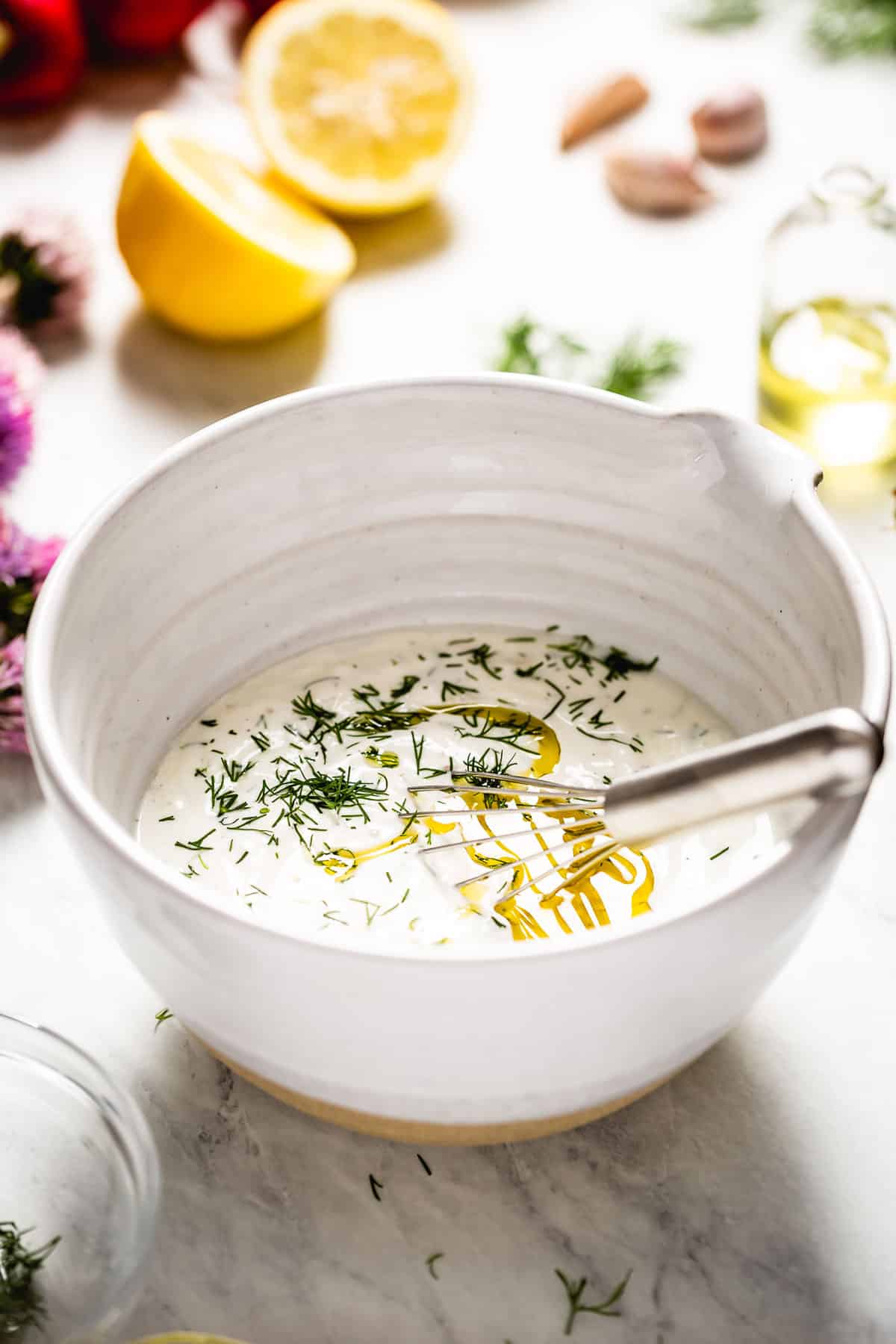 Yogurt sauce for salad in a bowl with a whisk.