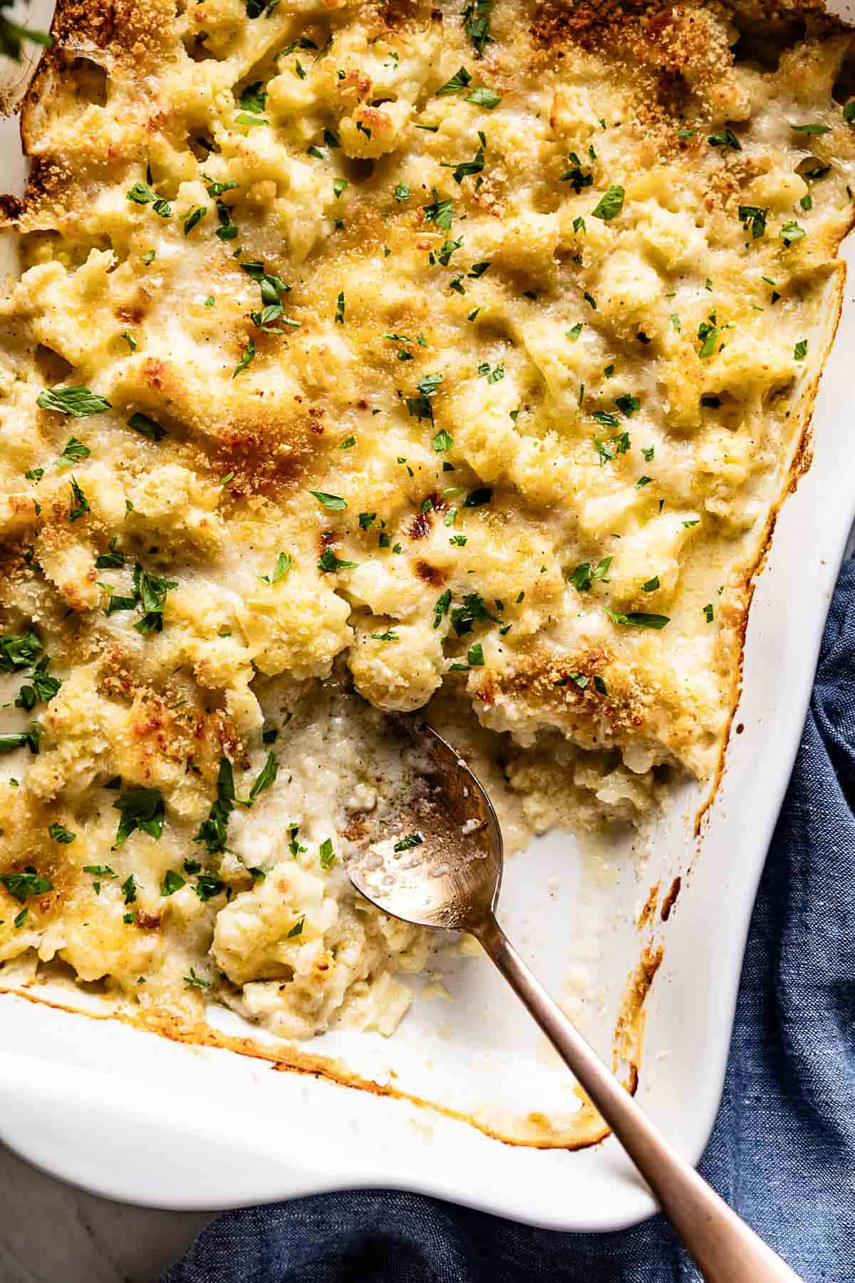 Cauliflower gratin in a casserole dish with a spoon on the side from the top view.