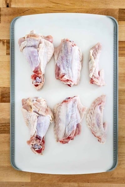 Turkey wings cut into parts on a cutting board from the top view.