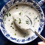 A bowl of horseradish yogurt sauce with a spoonful from the top view.