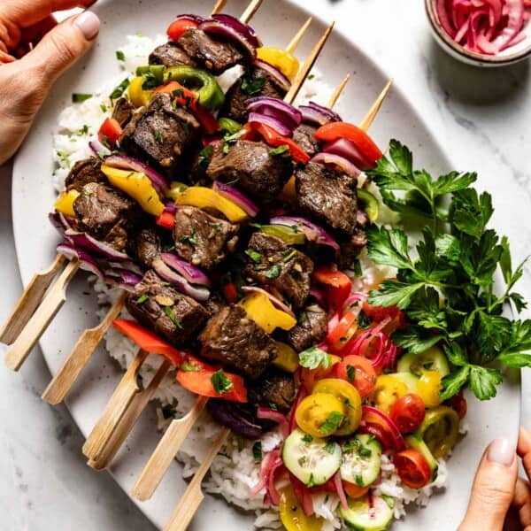 Baked beef kabobs on skewers on a bed of rice.