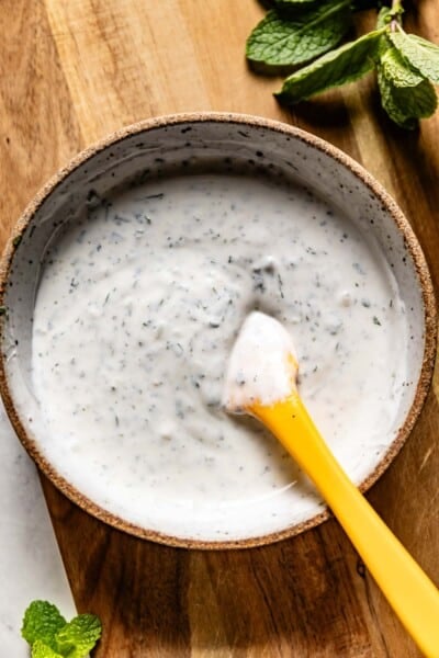 Mint yogurt sauce in a bowl with a small spatula from the top view.