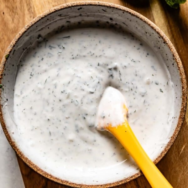 Mint yogurt sauce in a bowl with a small spatula from the top view.