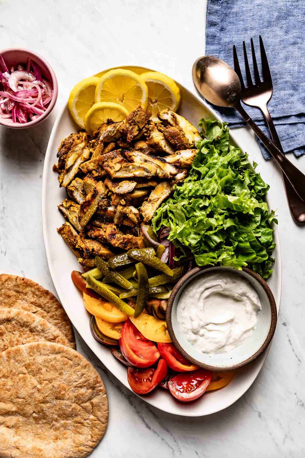 Chicken shawarma on a large plate served with toppings.