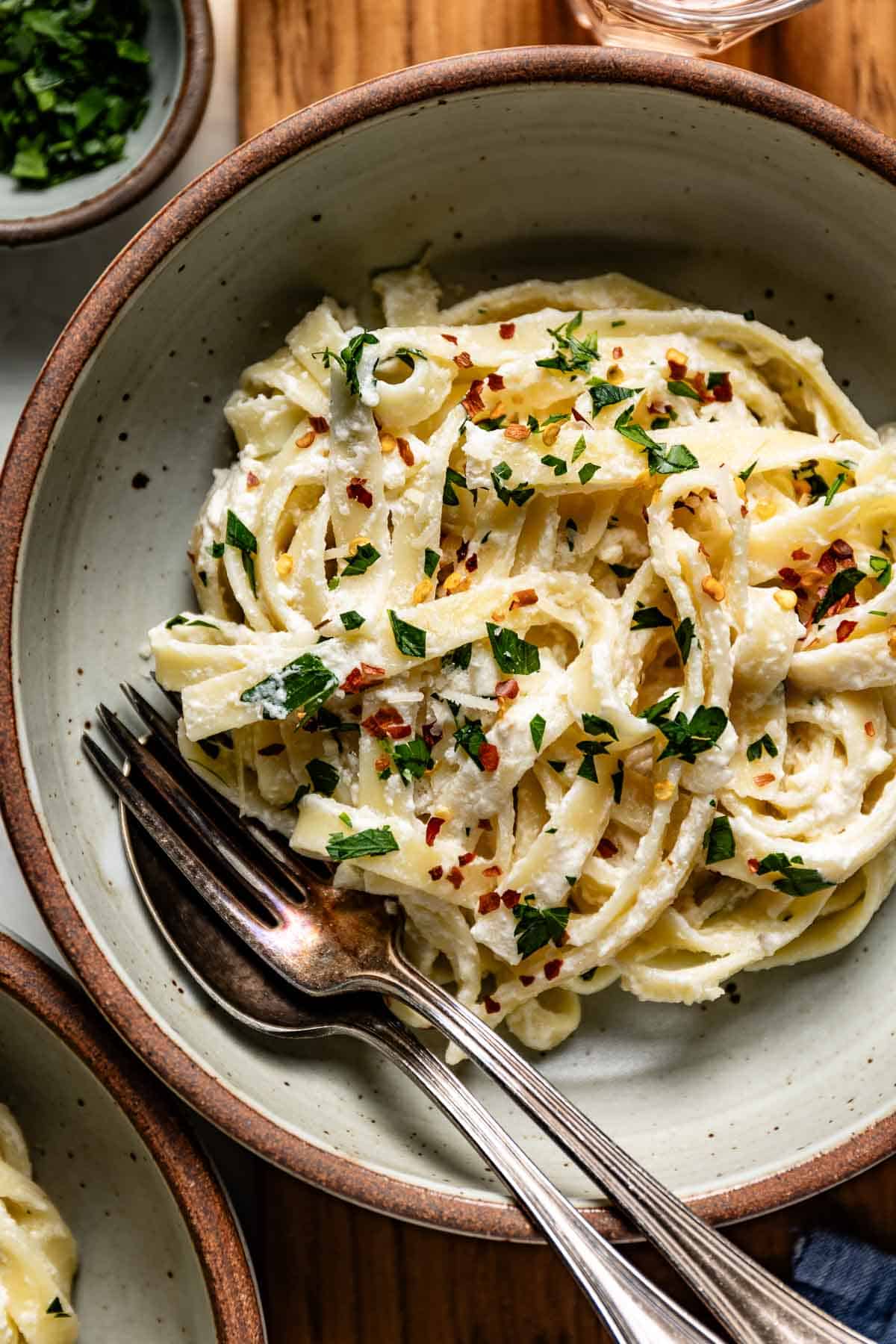 A bowl of fettuccine mixed with Greek yogurt pasta sauce and garnished with parsley.