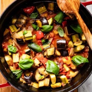 Easy ratatouille in a Dutch oven with a wooden spoon on the side.