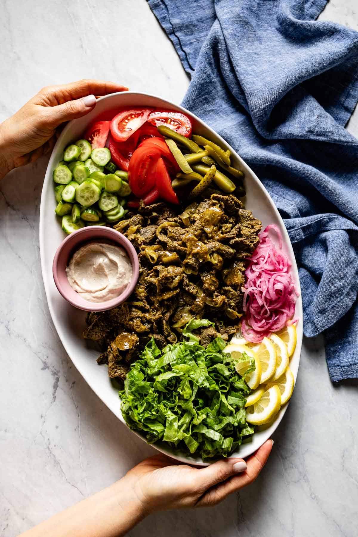 Beef shawarma platter being served by a person from the top view.