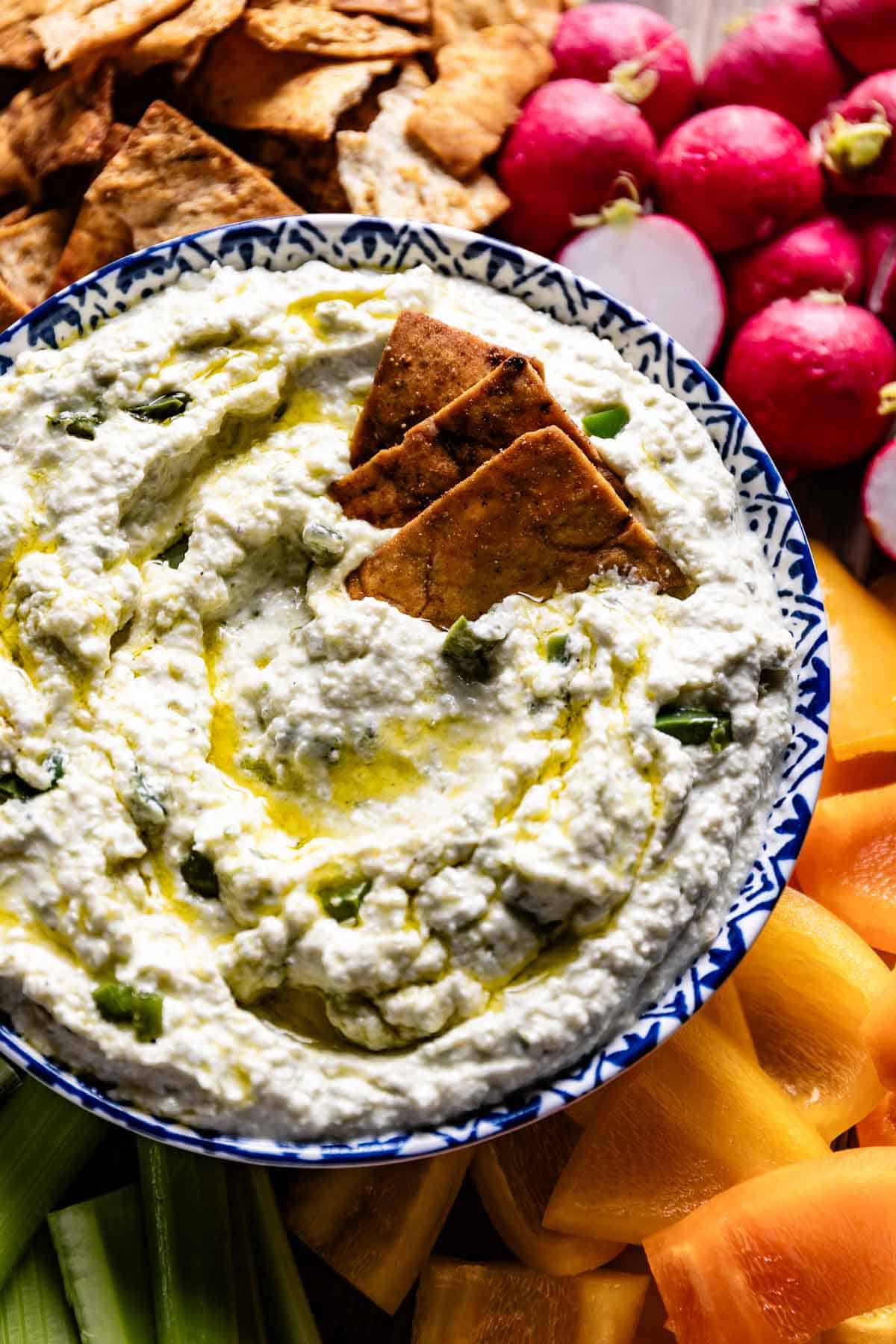 Cava feta dip served in a bowl with veggies and  pita chips from the top view.