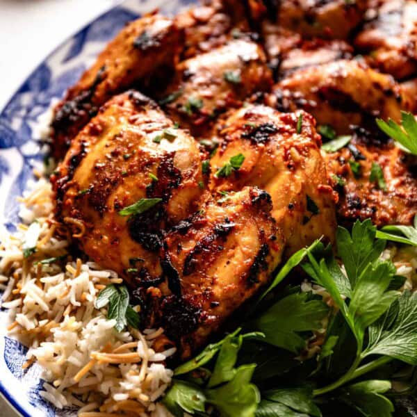 Grilled harissa chicken garnished with fresh parsley on a plate.