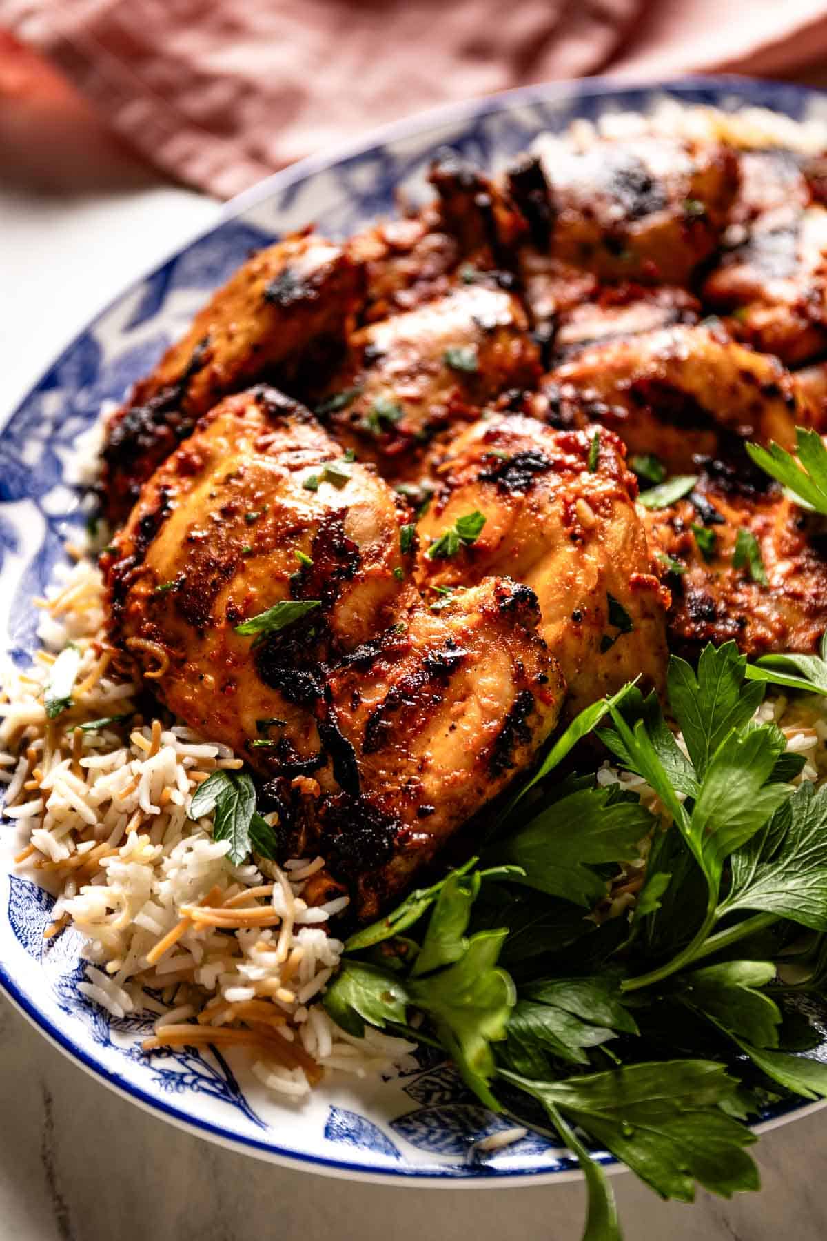 Grilled harissa chicken garnished with fresh parsley on a plate.