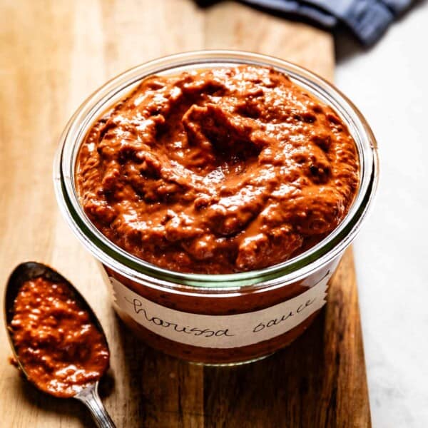 Harissa Sauce in a jar with a spoon on the side.