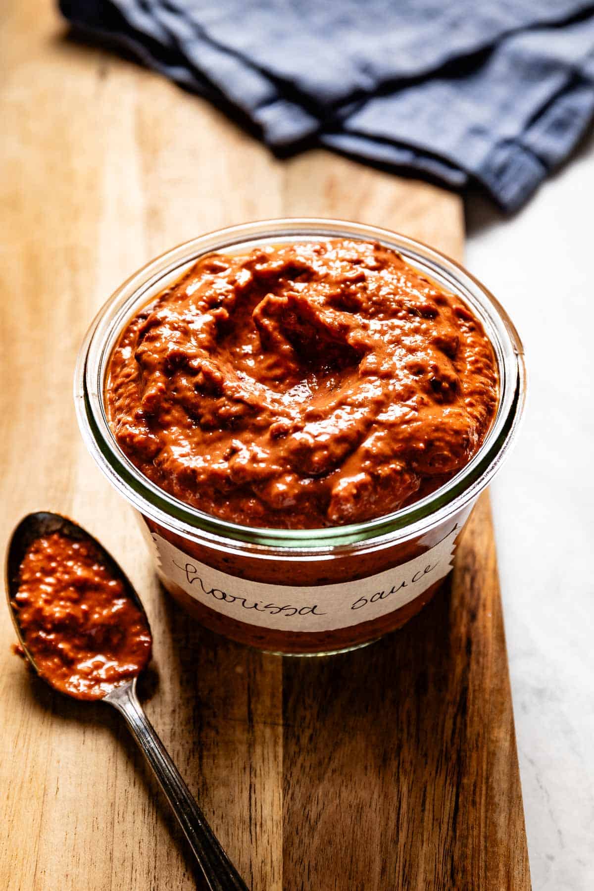 Harissa Sauce in a jar with a spoon on the side.