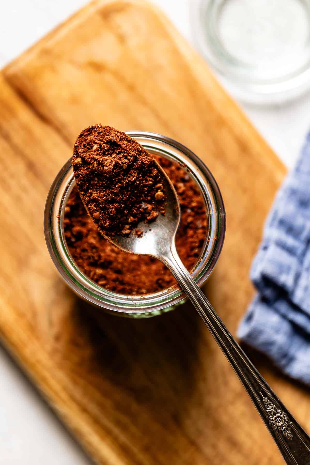 Harissa powder in a spoonful over a jar from the top view.