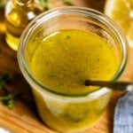A batch of my Homemade Mediterranean salad dressing recipe in a jar with a spoon.