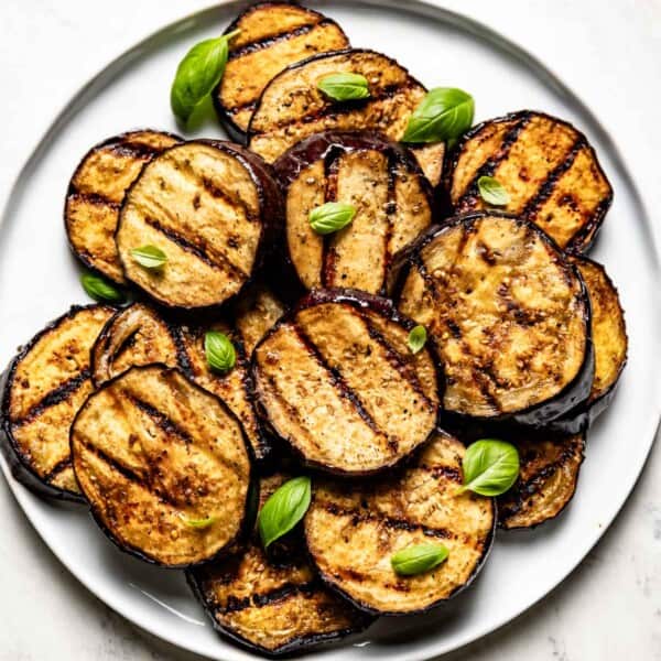 Grilled eggplant slices on a plate garnished with basil.