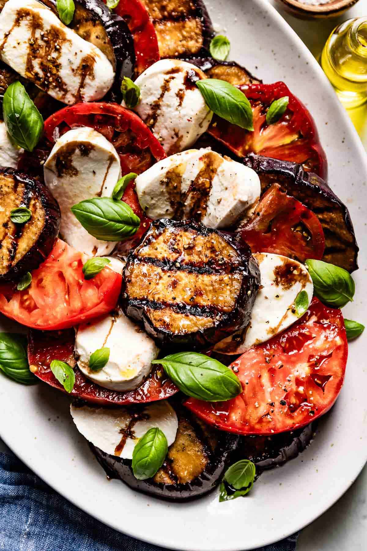 Eggplant Caprese on a plate garnished with basil leaves.